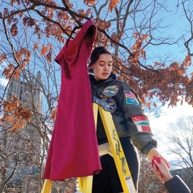 A photo shows Emma Slibeck ’24, president of NASA and a descendant of the Eastern Band of Cherokee Indians,  hanging a red dress from a tree on the Academic Quad as part of the REDress installation.