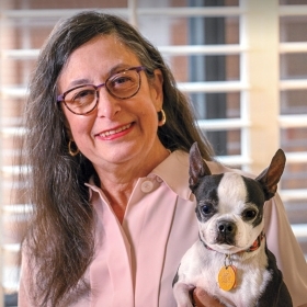 A portrait of Judy Rousuck '72 holding a small dog