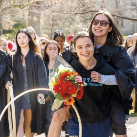 A photo of Emma Feldman ’24, this year’s Hooprolling champion, being carried toward Lake Waban.